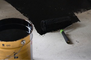 Basement waterproofing companies in Peoria IL applying sealant to a basement floor