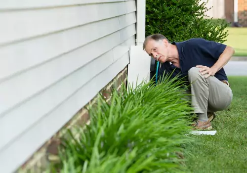 A man inspects a brick foundation. Basement Systems Waterproofing & Foundation perform Foundation Crack Repair in East Peoria IL.